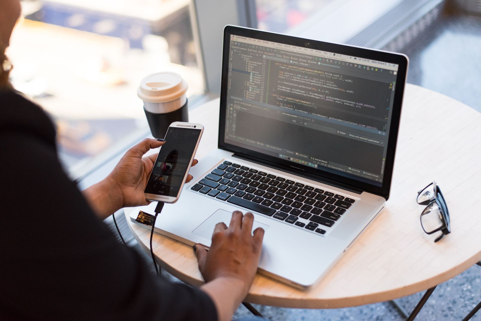 Developer testing a phone app beside a laptop